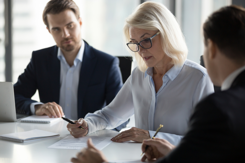 Businessmen,Sitting,At,Desk,Headed,By,Middle,Aged,Serious,Concentrated